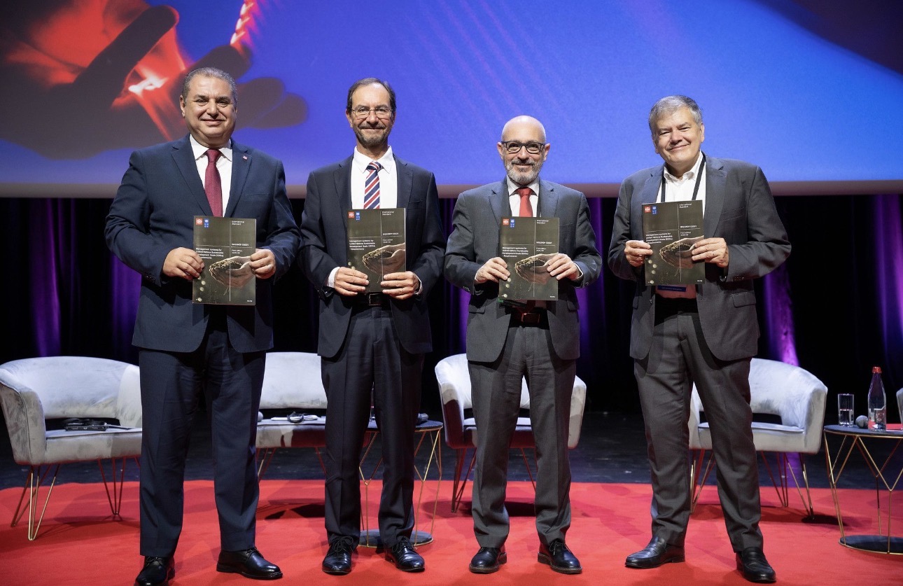 Quatro participantes em palco seguram exemplares da norma